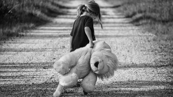 Junges Mädchen mit großem Teddy auf einem Weg.