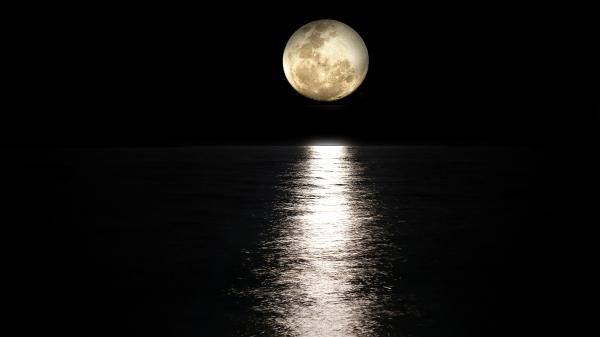 Sich im Meer spiegelndes Mondlicht bei Nacht.