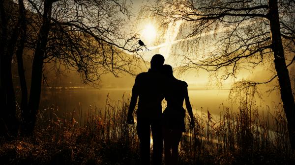 Silhouette eines Paares am Bergsee mit tiefstehender Sonne.