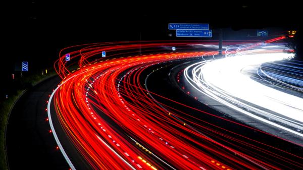 Rote und weiße Lichtbänder bei Nacht auf der Autobahn.