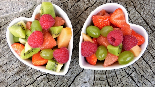 Zwei Keramikschälchen in Herzform gefüllt mit mundfertigem Obst.